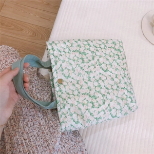 Détail d'un sac en coton matelassé à fleurs vert clair avec bouton pression métallique
