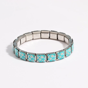 Macro detail of Italian charm bracelet links featuring blue enamel and daisy flowers