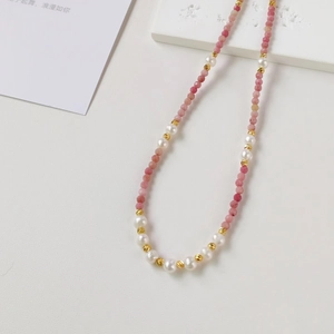 Detailed macro view of natural pink stones, freshwater pearls and golden metal spacer beads