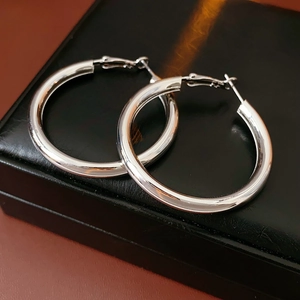 Close-up of classic silver hoop earrings resting on a black textured jewelry gift box