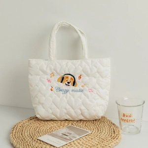 Close-up of white quilted heart patterns and cute cartoon dog embroidery on the tote bag