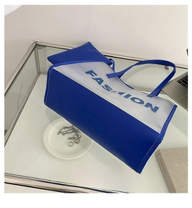 Detail view of blue and white fashion tote bag with inner pouch on a stylish desk