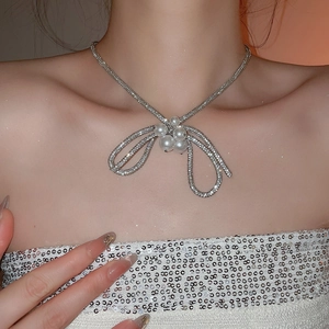 Close-up of elegant bow pendant necklace with pearls and diamonds on a model