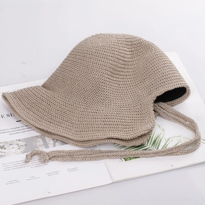 Close-up of khaki woven bucket hat with adjustable chin strap on a fashion magazine
