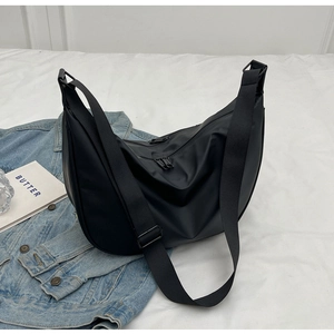 Detail of black crescent crossbody bag with wide adjustable strap and dual zippers
