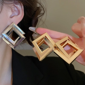 Detailed view of large geometric double square nested earrings in polished gold and silver