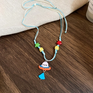 Gros plan d'un collier tressé coloré avec pendentif OVNI et perles multicolores