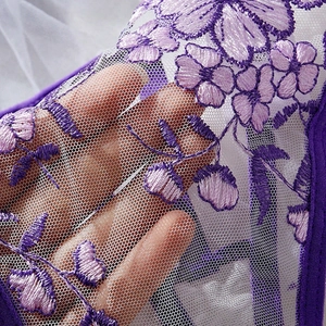 Close-up of purple lace mesh fabric with intricate floral embroidery details