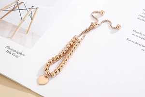 Detail of rose gold beaded bracelet with heart charm and adjustable sliding clasp closure