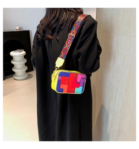 Detail of colorful geometric camera bag with wide woven strap and yellow leather