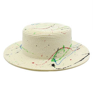 Close-up of fine woven straw hat with vibrant multi-color paint splatter and artistic design