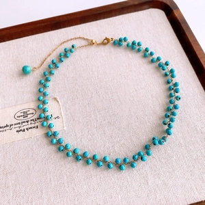 Détail d'un collier de perles turquoise avec une chaîne dorée réglable en acier