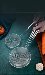 Detail view of stainless steel wire skimmer with ergonomic handle on a textured green background