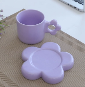 Detailed view of a purple ceramic mug with fat handle and flower-shaped saucer on a placemat