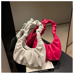 Close-up of pleated PU leather texture on white and magenta shoulder bags on a display
