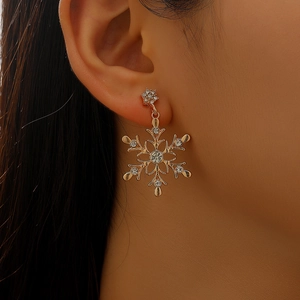 Detail of gold snowflake earrings with pearls and crystals worn on ear for party