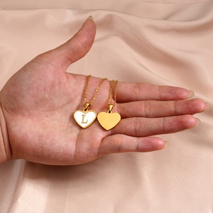 Gold heart pendant necklaces with shell inlay and letter L on silk background