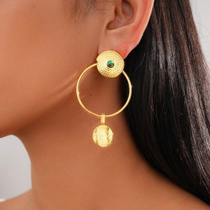 Detailed view of 24K gold plated earrings with green gemstone on model's ear