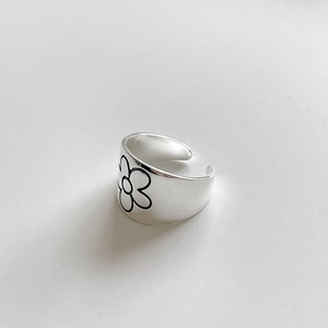 Detailed view of adjustable silver ring with black onyx flower pattern and wide band