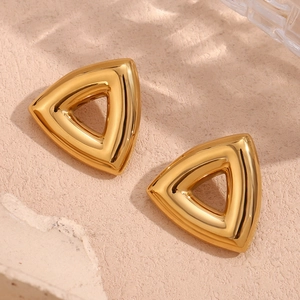 Macro detail of high-polished 18K gold-plated hollow triangle earrings on stone surface