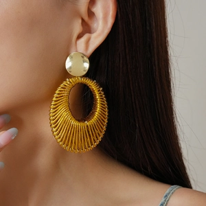 Close-up of gold velvet woven hollow oval earrings worn by a model in professional lighting