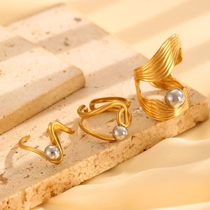 Detailed view of two-tone gold and silver irregular steel rings on stone and silk background