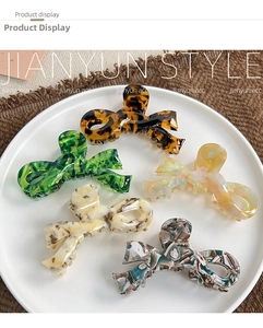 Detail of five marble patterned acetate bow hair claws in assorted vintage colors