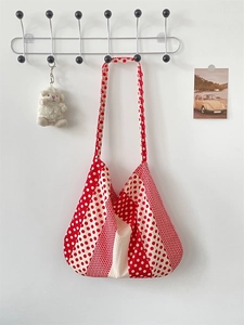 Detail view of red and white polka dot canvas shoulder bag hanging on a hook