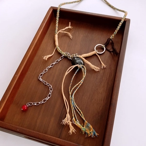 Détail d'un collier ethnique tressé avec pompon en bois et perles sur plateau bois