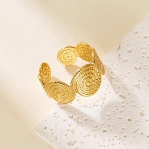 Close-up of golden open ring with spiral texture pattern on a white natural stone