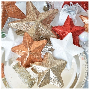 Glittering star and snowflake Christmas tree ornaments on a decorative silver tray