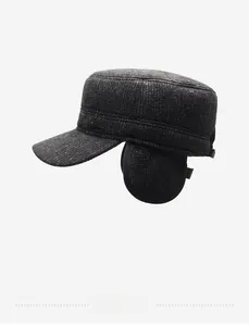 Detail of dark grey winter flat cap featuring fold-down ear flaps and metal logo