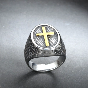 Détail de la bague hip-hop en acier titane avec croix dorée et texture noire