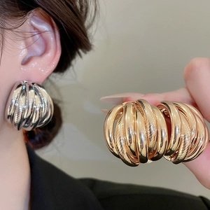 Detailed view of large multi-layer spiral hoop earrings in polished gold and silver finishes