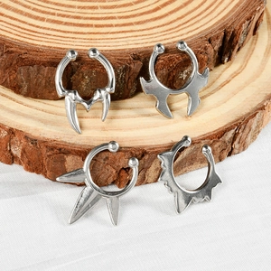 Minimalist U-shaped stainless steel faux nose rings with bat and spike designs on wood
