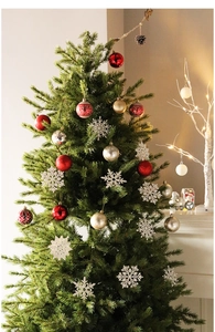 Close-up of red and gold Christmas ornaments and white snowflakes on a festive tree