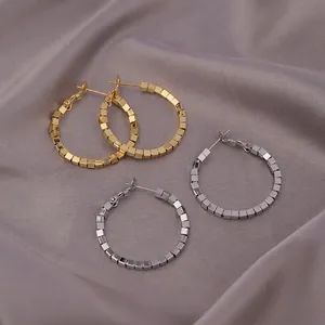 Chic geometric hoop earrings in gold and silver finish on elegant grey silk background