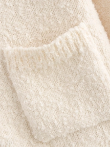 Macro shot of knit fabric texture and pocket detail on cream white bouclé sweater