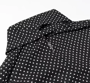 Detail des schwarzen Polka-Dot-Stoffs mit leichter Chiffon-Textur und dem Kragenbereich