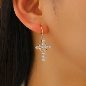 Macro shot of gold cross earrings with white zircon stones worn on the earlobe