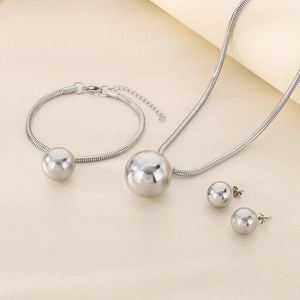 Detail view of silver stainless steel jewelry set with ball pendants on beige display