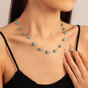 Détail du collier de cœurs en turquoise avec chaîne dorée sur un mannequin