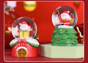 Close-up of festive Christmas snow globes with Santa Claus and Merry Christmas base