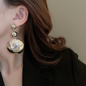 Detail of silver triple sphere drop earrings worn by a model in a minimalist style