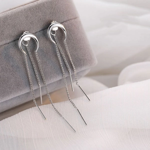 Dettaglio ravvicinato di orecchini a nappa lunga in argento con forma a mezzaluna