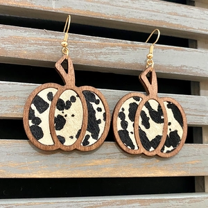 Detalle de pendientes de calabaza de madera con estampado de vaca y ganchos dorados