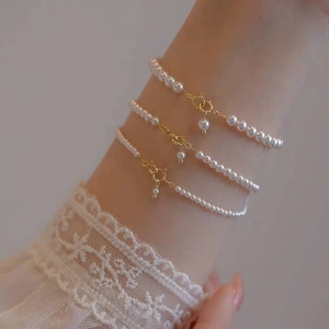 Elegant 14k gold pearl bracelet in various sizes worn on a wrist with lace cuffs