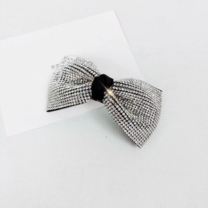 Macro detail of bow hair clip featuring silver rhinestones and black fabric knot