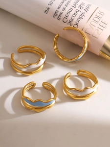 Set of four gold-plated wavy stackable rings with white and blue enamel accents