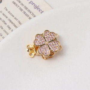 Detail of four-leaf flower jewelry clasp with pink zircons and gold-plated multi-row rings